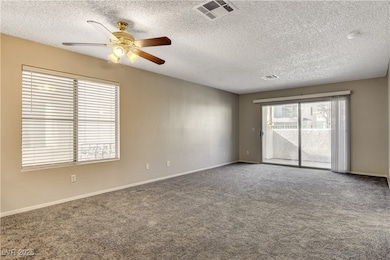 Carpeted empty room featuring a ceiling fan, a tex