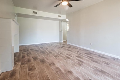 Empty room with a ceiling fan, wood finished floors, and baseboards