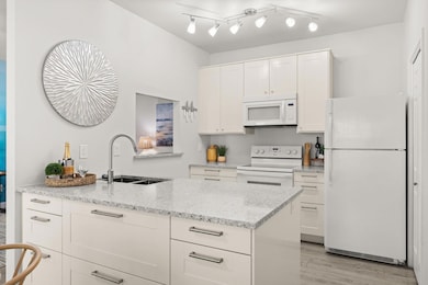 Kitchen featuring white appliances, a sink, white