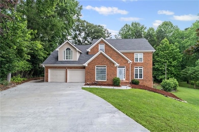 Traditional-style home featuring brick siding, driveway, a front lawn, a shingled roof, and an attached garage