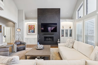 Living room with high vaulted ceiling, a premium fireplace, wood finished floors, and arched walkways