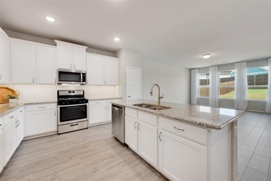 Kitchen with white cabinets, stainless steel appliances, sink, tasteful backsplash, and a kitchen island with sink
