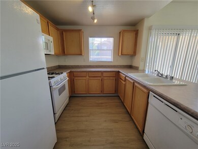 Kitchen featuring white appliances, a sink, light