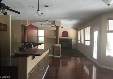 Kitchen featuring a ceiling fan, dark wood finished floors, a glass covered fireplace, healthy amount of natural light, and a textured ceiling