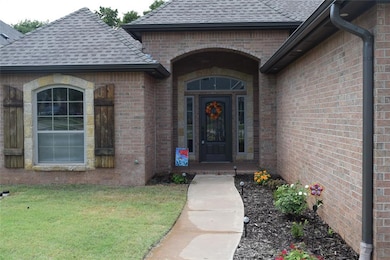Doorway to property featuring a shingled roof, brick siding, and a lawn