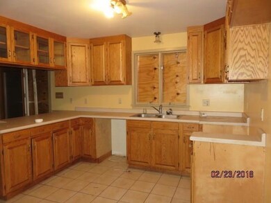 The kitchen has many cabinets, tile...
