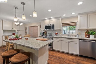 Kitchen featuring tasteful backsplash, light stone counters, dark wood-style floors, stainless steel appliances, and ornamental molding
