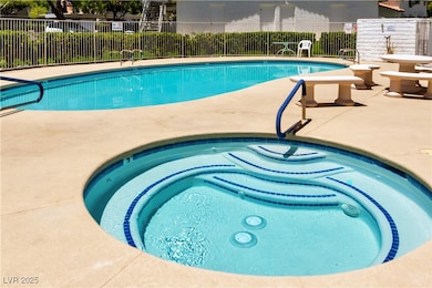 Pool featuring a patio area, fence, and a hot tub