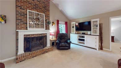 Carpeted living room with a fireplace and vaulted ceiling