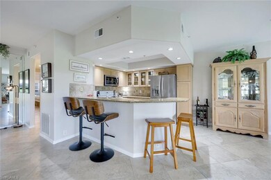 Kitchen with appliances with stainless steel finishes, glass insert cabinets, a breakfast bar, a peninsula, and light stone countertops