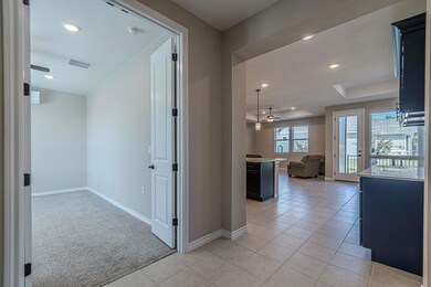 Corridor with a tray ceiling, recessed lighting, light carpet, and light tile patterned flooring