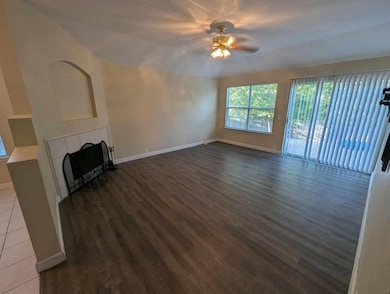 Unfurnished living room with a fireplace, dark wood-type flooring, and a ceiling fan