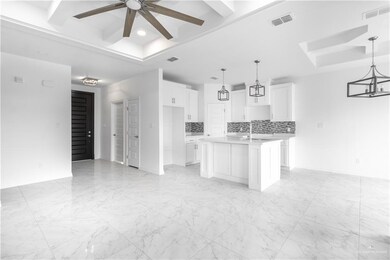 Kitchen featuring backsplash, hanging light fixtures, an island with sink, and ceiling fan