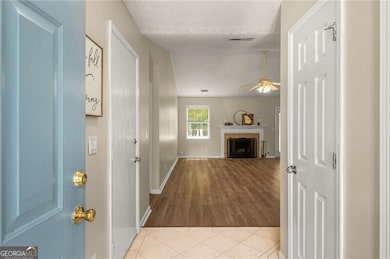 Foyer featuring ceiling fan, a tile fireplace, wood finished floors, and a textured ceiling
