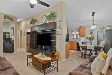 Living area featuring light carpet and a ceiling fan