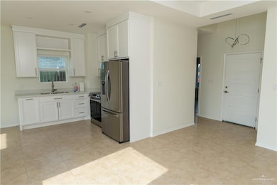 Kitchen with appliances with stainless steel finishes, light countertops, white cabinets, a sink, and visible vents