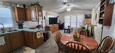 Kitchen with a textured ceiling, light carpet, ceiling fan, sink, and lofted ceiling