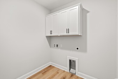 Laundry area with hookup for an electric dryer, baseboards, washer hookup, light wood finished floors, and cabinet space