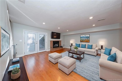 The living room has beautiful french doors and a wood burning fireplace. Photo is virtually staged.