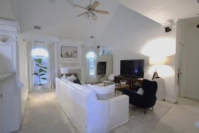 Living room featuring high vaulted ceiling, a ceiling fan, and light carpet
