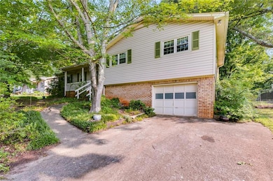 View of side of property with brick siding, a garage, and driveway
