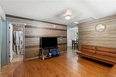 Living area featuring wood walls, wood finished floors, and a textured ceiling