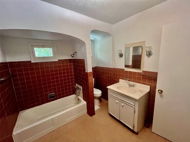 Bathroom featuring bathtub / shower combination, tile walls, vanity, wainscoting, and a textured ceiling