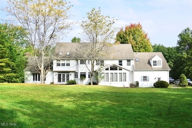 Rear view of house featuring a yard and a sunroom