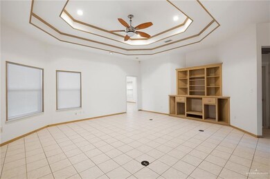 Unfurnished living room featuring a tray ceiling, light tile patterned floors, and ceiling fan