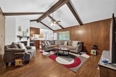 Grand family room with exposed beam ceilings and wood-look flooring, blending space and elegance.