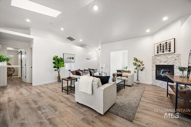 Living room featuring light wood-style floors, vaulted ceiling, recessed lighting, a fireplace, and a skylight
