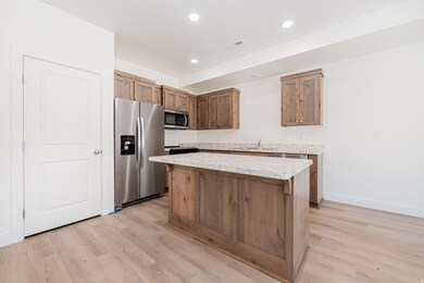 Kitchen featuring appliances with stainless steel finishes, light countertops, a center island, recessed lighting, and light wood-style floors
