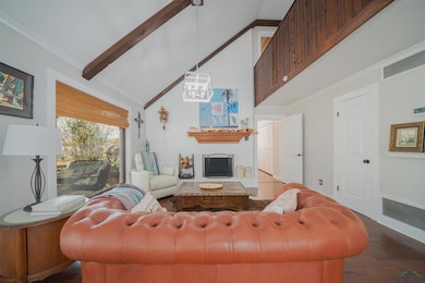 Living area with high vaulted ceiling, a fireplace, ornamental molding, beam ceiling, and dark wood-style floors
