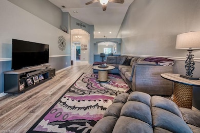 Living room with arched walkways, a high ceiling, light wood-type flooring, ceiling fan, and a chandelier