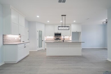 Kitchen featuring a kitchen island with sink, stai