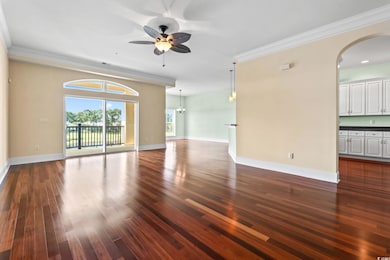 Unfurnished room with ornamental molding, dark wood-style floors, a ceiling fan, arched walkways, and a chandelier