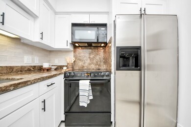 Galley kitchen with white cabinets, marble-style c