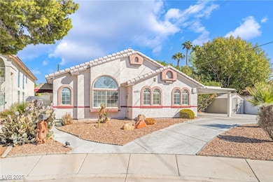 Mediterranean / spanish-style home featuring stucco siding, driveway, an attached carport, and an outbuilding