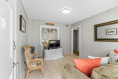 Living area with a decorative wall and light tile patterned flooring