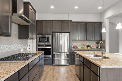 Kitchen with wall chimney exhaust hood, a sink, d
