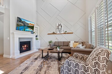 Living room featuring built in features, wood finished floors, a tiled fireplace, a high ceiling, and a decorative wall