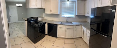 Kitchen with black appliances, light tile patterned floors, pendant lighting, light stone countertops, and backsplash