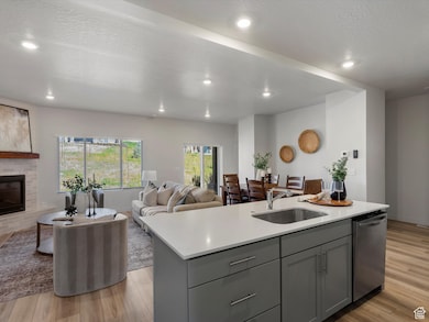 Kitchen featuring gray cabinetry, light wood-type flooring, a fireplace, an island with sink, and a textured ceiling