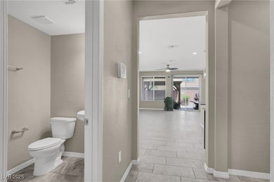 Bathroom with toilet, a ceiling fan, and baseboard