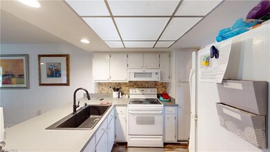 Kitchen with white cabinetry, white appliances, si