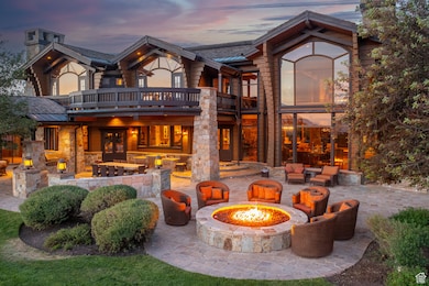 Back of property at dusk featuring a patio area, a balcony, and an outdoor living space with a fire pit