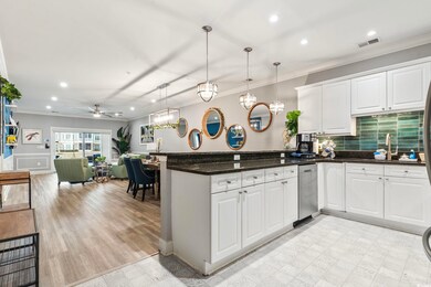 Kitchen featuring ornamental molding, dark stone countertops, hanging light fixtures, and white cabinets