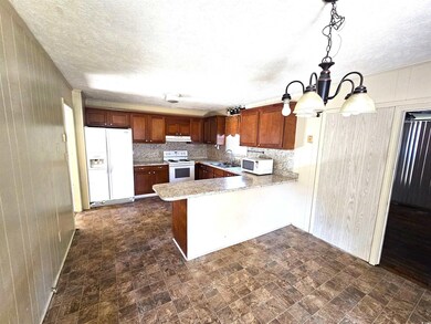Kitchen with white appliances, a peninsula, a sink, light countertops, and under cabinet range hood