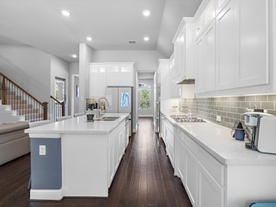 Kitchen featuring an island with sink, white cabinets, backsplash, glass insert cabinets, and recessed lighting