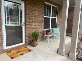Doorway to property featuring a porch and brick siding